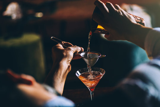Bartender straining a craft cocktail